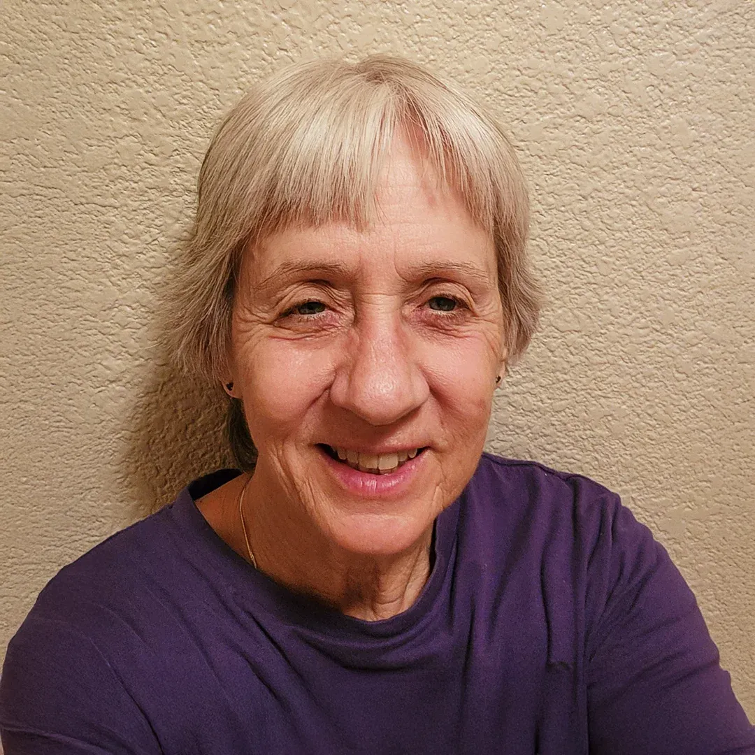 Portrait Of Nancy McKernan Smiling Against A Textured Wall Nancy McKernan smiling while standing against a textured wall indoors